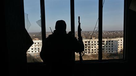 Ein Soldat schaut auf zerstörte Gebäude in Saporischja.