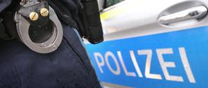ARCHIV - 15.03.2019, Bayern, Kempten: Ein Polizist mit Handschellen und einer Pistole am Gürtel steht vor einem Streifenwagen. (zu dpa: «Mann verletzt jugendlichen Patienten mit Messer») Foto: Karl-Josef Hildenbrand/dpa +++ dpa-Bildfunk +++