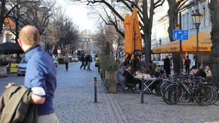 Menschen flanieren in der Dortustraße und sitzen an Tischen unter freiem Himmel.