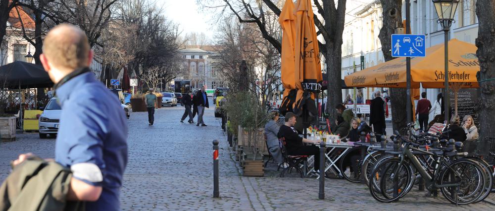 Menschen flanieren in der Dortustraße und sitzen an Tischen unter freiem Himmel.