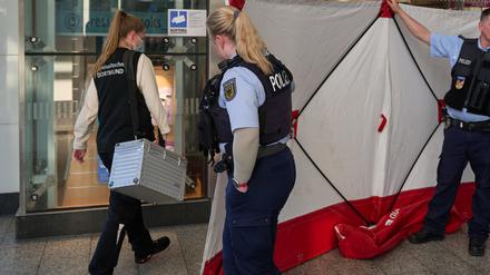 Polizisten öffnen den Sichtschutz vor einem Geschäft im Hauptbahnhof für eine Mitarbeiterin der Kriminaltechnik. Im Hauptbahnhof Dortmund ist am Mittag ein Mitarbeiter eines Fahrkartenschalters von einem Mann mit einem Messer angegriffen worden. 