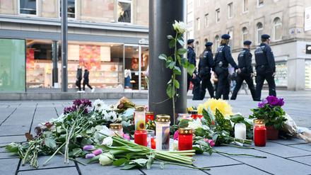 Kerzen und Blumen liegen in der Nähe des Paradeplatzes in Mannheim an einer Straßenbahnhaltestelle.