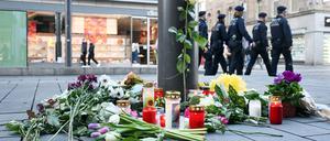 Kerzen und Blumen liegen in der Nähe des Paradeplatzes in Mannheim an einer Straßenbahnhaltestelle.