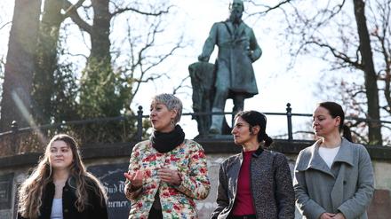 Kathy Herrmann Aguero (v.l.), Grünen Fraktion Neukölln, Susanna Kahlefeld, Sprecherin für Engagement und Beteiligung der Grünen Fraktion im Berliner Abgeordnetenhaus, Bahar Haghanipour, Frauenpolitische Sprecherin der Grünen Fraktion im Berliner Abgeordnetenhaus, und Bezirksstadträtin Janine Wolter (SPD) stehen vor einem Denkmal für Friedrich Ludwig Jahn.
