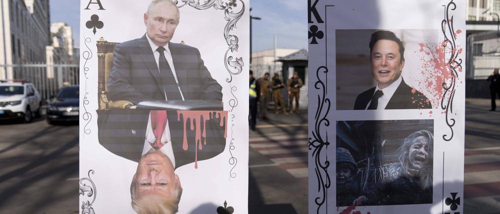 PLakate mit den Konterfeis von Putin, Trump und Musk bei Protesten vor der amerikanischen Botschaft in Kiew.