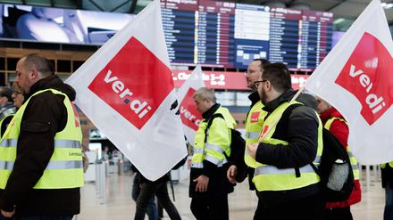 Mitarbeiter des Luftsicherheitspersonals demonstrieren mit Fahnen der Dienstleistungsgewerkschaft Verdi in der Abflughalle im Terminal 1 des Flughafens BER. 