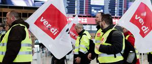 Mitarbeiter des Luftsicherheitspersonals demonstrieren mit Fahnen der Dienstleistungsgewerkschaft Verdi in der Abflughalle im Terminal 1 des Flughafens BER. 