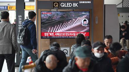Menschen sehen auf einem Fernsehbildschirm in einem Bahnhof in Seoul eine Nachrichtensendung mit Filmmaterial über einen nordkoreanischen Raketentest.