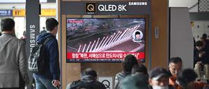 Menschen sehen auf einem Fernsehbildschirm in einem Bahnhof in Seoul eine Nachrichtensendung mit Filmmaterial über einen nordkoreanischen Raketentest.