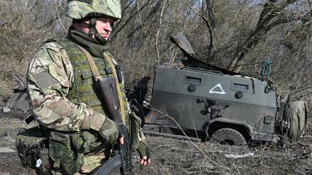 Ein russischer Soldat geht an einem zerstörten ukrainischen gepanzerten Mannschaftstransportwagen vorbei, als er in der Siedlung Pogrebki inmitten der russischen Militäroperation in der Ukraine in der Region Kursk patrouilliert.