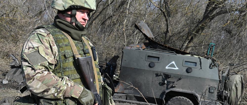 Ein russischer Soldat geht an einem zerstörten ukrainischen gepanzerten Mannschaftstransportwagen vorbei, als er in der Siedlung Pogrebki inmitten der russischen Militäroperation in der Ukraine in der Region Kursk patrouilliert.