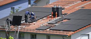 Einfamilienhaus mit Photovoltaikanlage: Arbeiter bei der Montage von Solarpanels auf einem Hausdach. 