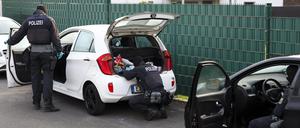 Polizeibeamte durchsuchen mehrere Pkw vor einem Wohnhaus. 
