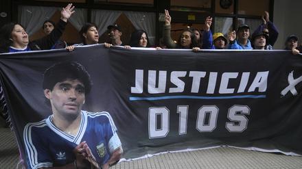 Fans des verstorbenen Fußballstars Diego Maradona halten ein Transparent mit der spanischen Aufschrift „Gerechtigkeit für Gott“ vor dem Gericht.