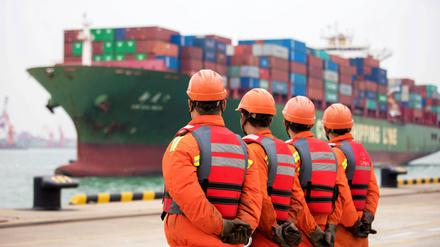 Arbeiter warten im Hafen von Qingdao in der chinesischen Provinz Shandong auf das Entladen von Schiffscontainern.