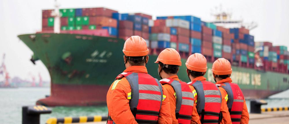 Arbeiter warten im Hafen von Qingdao in der chinesischen Provinz Shandong auf das Entladen von Schiffscontainern.