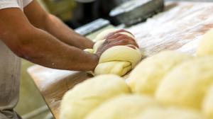 Ein Bäcker knetet in der Backstube einer Bäckerei Brotteig. (Symbolbild)
