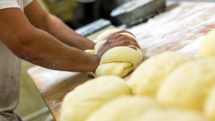 Ein Bäcker knetet in der Backstube einer Bäckerei Brotteig. (Symbolbild)