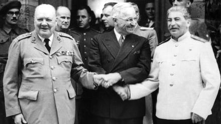 Der britische Premierminister Winston Churchill (l.), der amerikanische Präsident Harry S. Truman (M.) und der sowjetische Diktator Josef Stalin reichen sich während der Potsdamer Konferenz vor Schloss Cecilienhof die Hände.