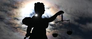 Eine Figur der Justitia steht vor wolkigem Himmel im Gegenlicht (Symbolbild)