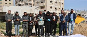 Männer beten über Leichen, nachdem palästinensische Mitarbeiter des Zivilschutzes am 13. März 2025 auf dem Gelände des Al-Shifa-Krankenhauses in Gaza-Stadt vergrabene Leichen entdeckt haben. Das Al-Shifa-Krankenhaus, einst der Stolz der medizinischen Gemeinschaft des Gazastreifens, ist zu einem Symbol der völligen Verwüstung geworden, die der Krieg zwischen Israel und der Hamas angerichtet hat