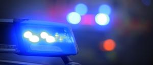 Ein Polizeiauto mit eingeschaltetem Blaulicht steht an einer Unfallstelle. 