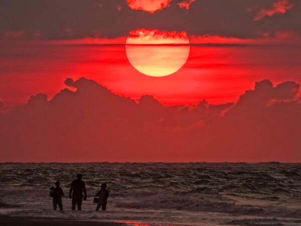August 10, 2023, Isle Of Palms, SC, United States: A family stands in the ocean as they watch the sunrise over the Atlantic Ocean on another record hot and muggy day in the Charleston area, August 10, 2023 in Isle of Palms, South Carolina. A persistent heat wave across the southern United States continues to bring extremely hot, humid weather to the region. Isle Of Palms United States - ZUMAe02_ 20230810_zaf_e02_001 Copyright: xRichardxEllisx
