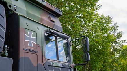 Detailansicht eines Rheinmetall HX-LKWs der Bundeswehr mit dem Bundeswehrkreuz auf der Tür. Der militärische LKW ist in Tarnfarben lackiert, umgeben von grüner Vegetation im Hintergrund.