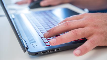 Finger tippen auf der Tastatur eines Laptops.
