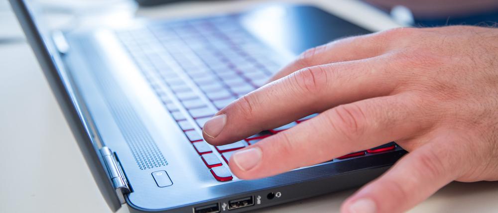 Finger tippen auf der Tastatur eines Laptops.