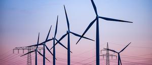 Windkraftanlagen und Hochspannungsleitungen sind vor dem Abendhimmel bei Leuna zu sehen.