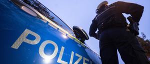 Eine Polizistin steht neben einem Polizeifahrzeug. 
