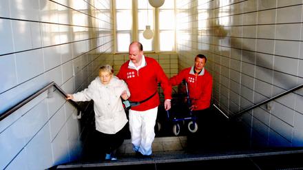 Berlin der VBB-Begleitservice ein Service des Berliner Verkehrsverbundes - bringt Menschen zum Nahverkehrsmittel oder holt sie dort ab. Frau Renate Brix (84) läßt sich von Andreas Goschning und Zdenek Klimes zur U-Bahn begleiten. Ihre Wohnung ist in der Krautstraße im 5.Stock sie muss zum U-Bahnhof Strausßberger Platz. Foto: doris spiekermann-klaas