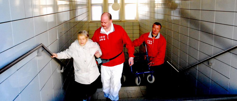 Berlin der VBB-Begleitservice ein Service des Berliner Verkehrsverbundes - bringt Menschen zum Nahverkehrsmittel oder holt sie dort ab. Frau Renate Brix (84) läßt sich von Andreas Goschning und Zdenek Klimes zur U-Bahn begleiten. Ihre Wohnung ist in der Krautstraße im 5.Stock sie muss zum U-Bahnhof Strausßberger Platz. Foto: doris spiekermann-klaas