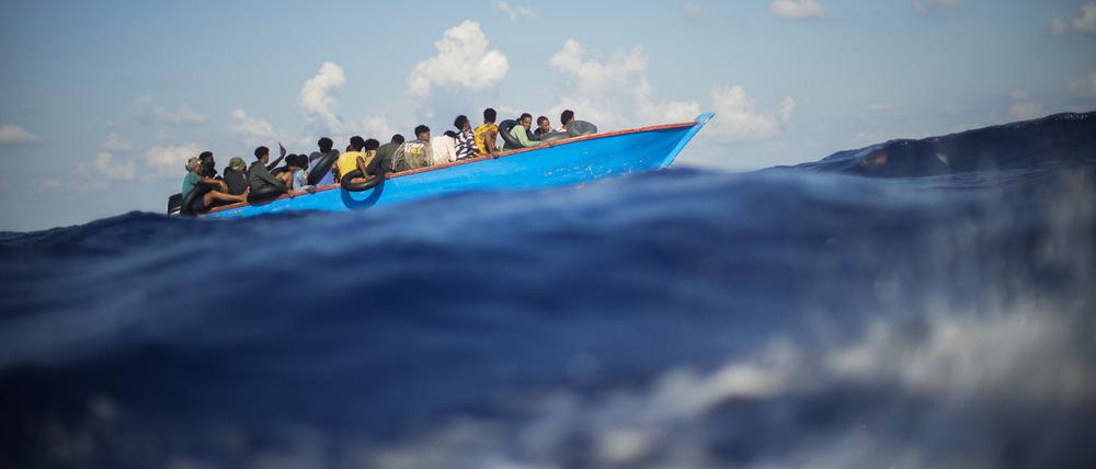 Migranten sitzen in einem Holzboot im Mittelmeer.