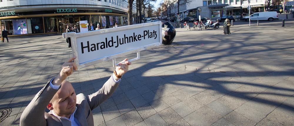 Felix Recke-Friedrich (FDP), Fraktionsvorsitzender in der Bezirksverordnetenversammlung Charlottenburg-Wilmersdorf, steht mit einem Straßenschild und der Aufschrift «Harald-Juhnke-Platz» an der Straßenecke Kurfürstendamm/Uhlandstraße/Grolmanstraße.