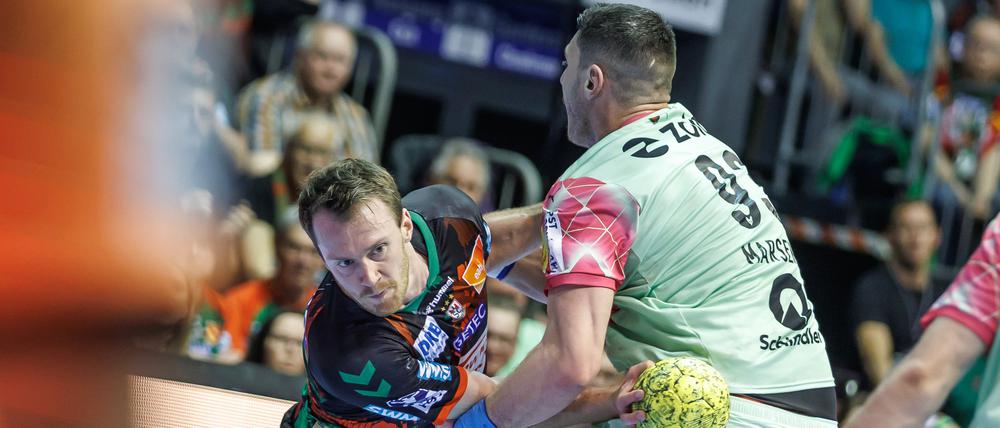 Felix Claar von SC Magdeburg wird festgemacht von Berlins Mijajlo Marsenic (r).