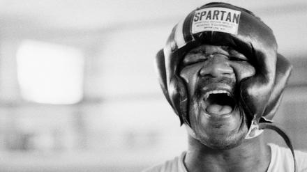George Foreman lacht unter seiner Kopfbedeckung in N’Sele, Zaire, nachdem er die ersten Sparringsrunden geboxt hat, 15. Oktober 1974. 