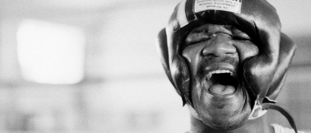 George Foreman lacht unter seiner Kopfbedeckung in N’Sele, Zaire, nachdem er die ersten Sparringsrunden geboxt hat, 15. Oktober 1974. 