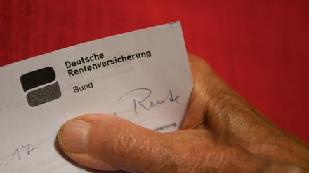 Eine ältere Frau hält ihren Rentenbescheid in der Hand.