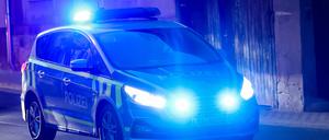 Ein Fahrzeug der Polizei fährt mit Blaulicht am Abend durch eine enge Straße. (Symbolbild)