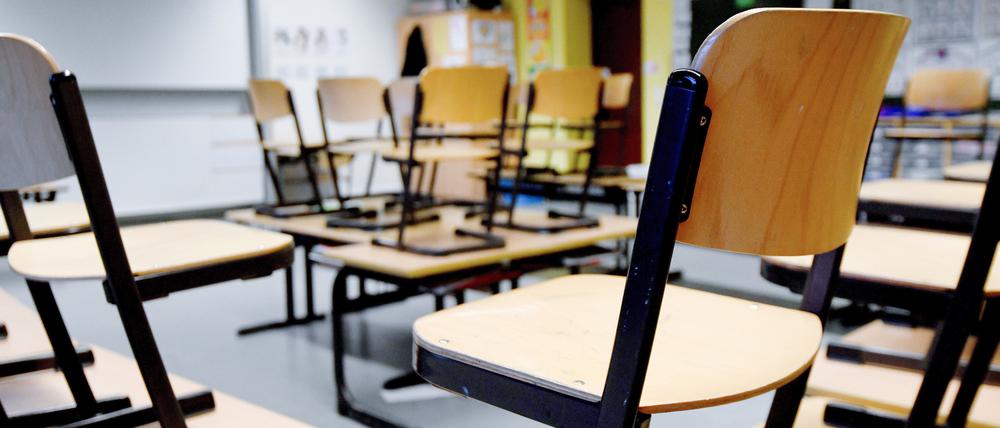 Stühle stehen in einem Klassenzimmer in einer Grundschule auf den Tischen. 