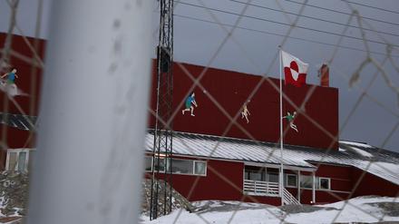 Eine grönländische Flagge weht in Ilulissat zwischen einem zugeschneiten Fußballplatz und einer Sporthalle.