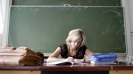 Lehrerin korrigiert Hefte im Klassenzimmer.