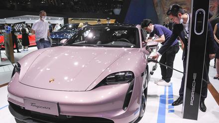 Besucher betrachten den elektrischen Porsche Taycan vom Automobilhersteller Porsche auf der Internationale Automesse. 