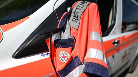 Eine Jacke eines Rettungssanitäters des Deutschen Roten Kreuzes hängt am Fenster eines Krankenwagens. (Symbolbild)