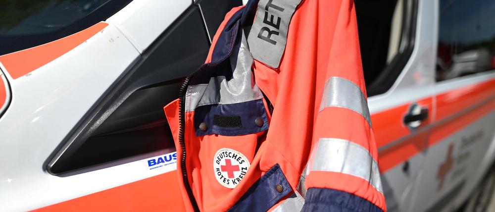 Eine Jacke eines Rettungssanitäters des Deutschen Roten Kreuzes hängt am Fenster eines Krankenwagens. (Symbolbild)