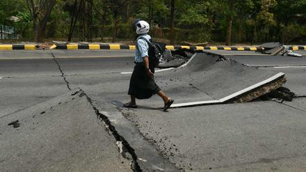 Ein Mann geht am 28. März 2025 nach einem Erdbeben in Zentral-Myanmar eine beschädigte Straße in Naypyidaw entlang.