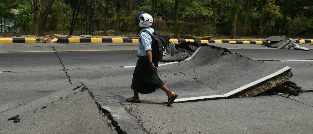 Ein Mann geht am 28. März 2025 nach einem Erdbeben in Zentral-Myanmar eine beschädigte Straße in Naypyidaw entlang.