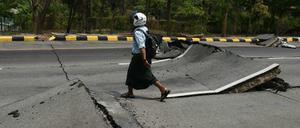 Ein Mann geht am 28. März 2025 nach einem Erdbeben in Zentral-Myanmar eine beschädigte Straße in Naypyidaw entlang.